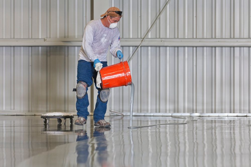 Epoxy Pros technician scraping and preparing the concrete floor surface before epoxy coating application